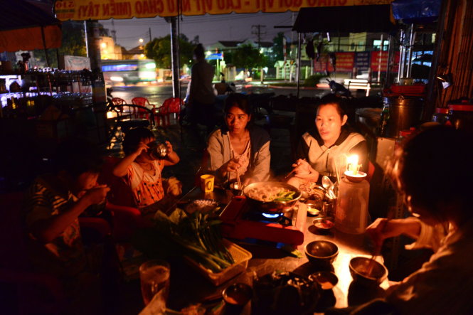 Một gia đình thắp nến ăn cơm khi mưa ngập, cúp điện ở đường Kinh Dương Vương - Ảnh: Thanh Tùng