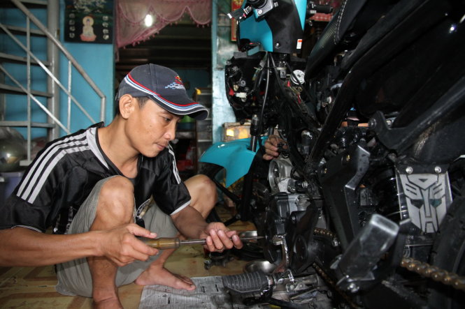 Nguyễn Thanh Vũ sửa xe máy tại nhà - Ảnh: T.P.