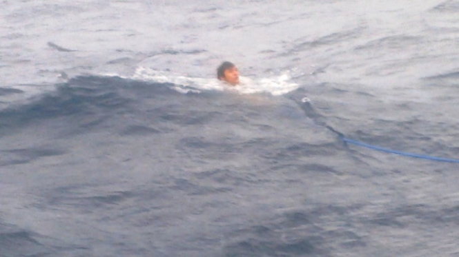 Một ngư dân gặp nạn bám theo dây được quăng xuống để được cứu sống (Ảnh cắt từ camera do ngư dân cung cấp cho PV Tuổi Trẻ)