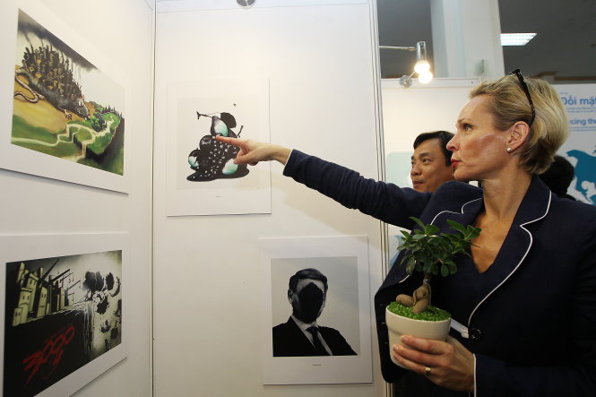 Đại sứ Thụy Điển tại Việt Nam Camilla Mellander chăm chú theo dõi một bức biếm họa tại triển lãm - Ảnh: Nguyễn Khánh