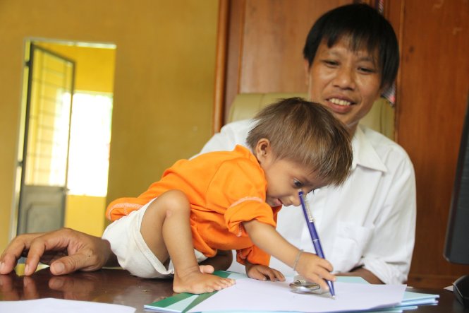 Thầy Cương hướng dẫn bé K'Rể cách cầm bút và viết những gì mình thích - Ảnh: T.MAI