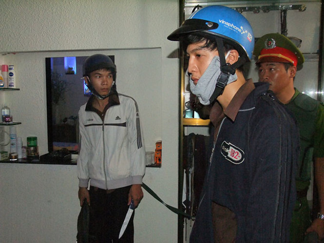 Dương (bìa phải) và Tiến (bìa trái) cầm con dao hung khí tại hiện trường thực nghiệm - Ảnh: N. NG.