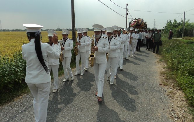 Đội nhạc nữ (chị Toan chỉ huy đi giật lùi) phục vụ một đám tang - Ảnh H.Tùng