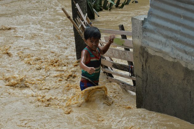Một bé trai đứng trước ngôi nhà bị ngập lụt trong bão Koppu ở tỉnh Aurora ngày 19-10 - Ảnh: AFP