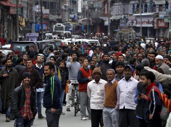 People stand on a road after vacating buildings following an earthquake in Srinagar October 26, 2015.