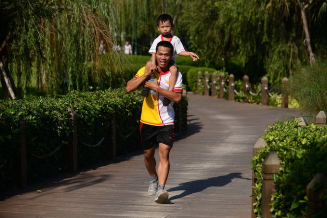 Một em nhỏ tham gia chạy cùng cha mình - Ảnh: Quang Định