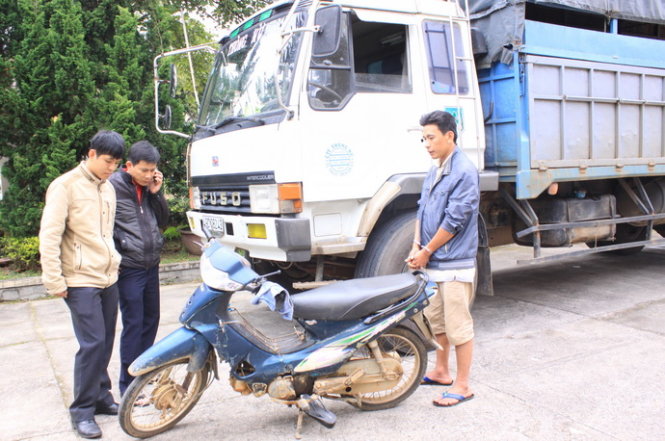 Lái xe Trương Hồng Duy (bị còng tay) bên chiếc xe tải gây tai nạn - Ảnh Đức Huy