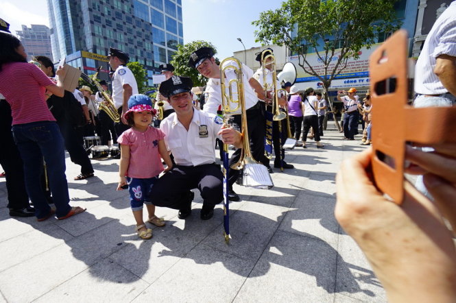 Các nghệ sĩ thuộc đoàn nhạc cảnh sát TP New Yor, Mỹ thân thiện chụp ảnh cùng một em bé Việt Nam tển phố đi bộ Nguyễn Huệ, Q,1, TP.HCM - Ảnh: Quang Định