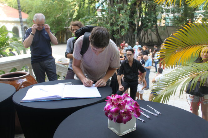 Một người viết vào sổ chia buồn ở Lãnh sự quán Pháp chiều 14-11 - Ảnh: Bình Minh