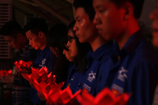 Các bạn sinh viên và thanh niên tình nguyện thắp nến tưởng nhớ nạn nhân - Ảnh: NAM TRẦN