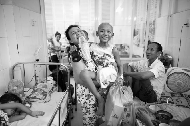 Nguyễn Thanh Tuấn 9 tuổi ở Ninh Thuận rạng ngời khi được mẹ bế đi chơi đồ chơi mới. Tuấn bị ung thư xương. Chân em mới cắt được hơn 2 tuần, bộ đồ chơi là quà tặng của các mạnh thường quân hứa cho khi chân em cắt chỉ - Ảnh: Thuận Thắng