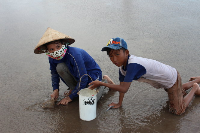 Nhiều trẻ em vùng ven biển của tỉnh Bạc Liêu hằng ngày phải theo cha mẹ mò nghêu mưu sinh nên không thể đến trường - Ảnh: Tiến Trình