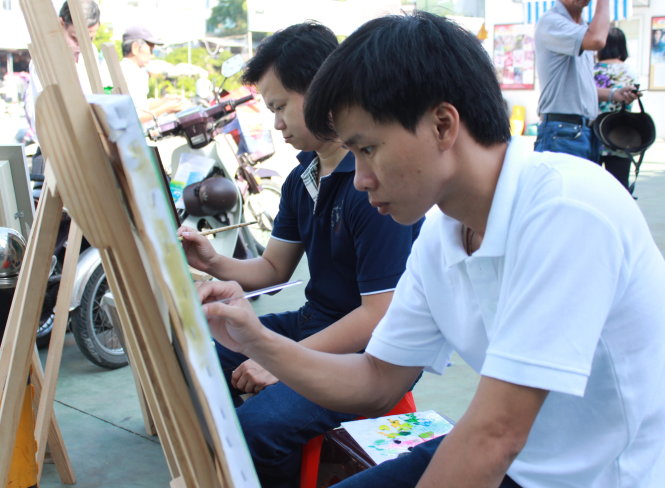 Hai bạn Lê Ngọc Tân và Nguyễn Hùng Hiếu (từ phải qua) - học viên nghề hội họa của Trung tâm Bảo trợ, dạy nghề và tạo việc làm cho người tàn tật - biểu diễn vẽ tranh tại chương trình - Ảnh: Q.L.