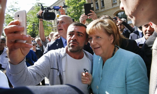 Thủ tướng Merkel chụp ảnh cùng người nhập cư gần trại tị nạn ở Berlin ngày 10-9 - Ảnh: Reuters