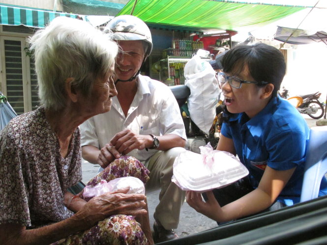 Bạn Nguyễn Thị Nhật Hiền (bìa phải) cùng anh Phạm Minh Thành  đưa cơm cho cụ Nguyễn Thị Hương, 82 tuổi - Ảnh: K.Anh