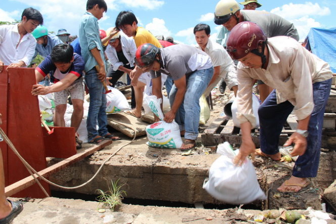 Đóng cừ và lấy bao cát đắp bờ để bơm cạn nước trong vùng tìm kiếm. ẢNH: BÁ SƠN