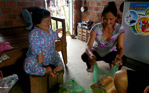 Chị Nga với công việc thường ngày trên đôi chân bằng ghế gỗ - Ảnh: B.D.