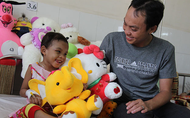 Bé Kim Ngân vui cười bên anh Trần Văn Tố - Ảnh: Bá Sơn