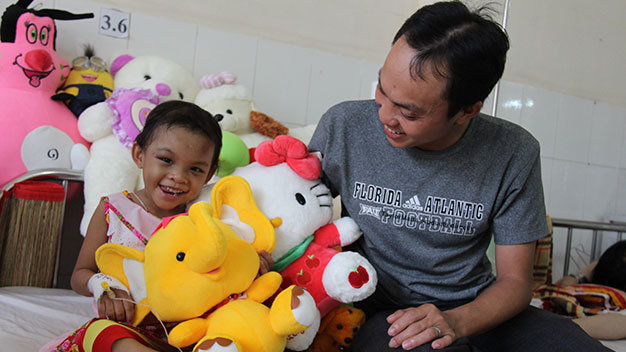 Bé Kim Ngân vui cười bên anh Trần Văn Tố - Ảnh: Bá Sơn