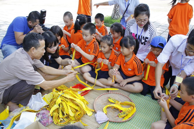 Nghệ nhân dân gian hướng dẫn các em nhỏ làm con giống chuyển động - Ảnh: Đ.Triết