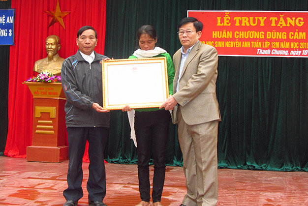 Ông Thái Huy Vinh- phó giám đốc sở GD-ĐT Nghệ An trao “Huân chương dũng cảm” của Chủ tịch nước cho bà Nguyễn Thị kim (mẹ Tuấn) - Ảnh: Nhật Đức