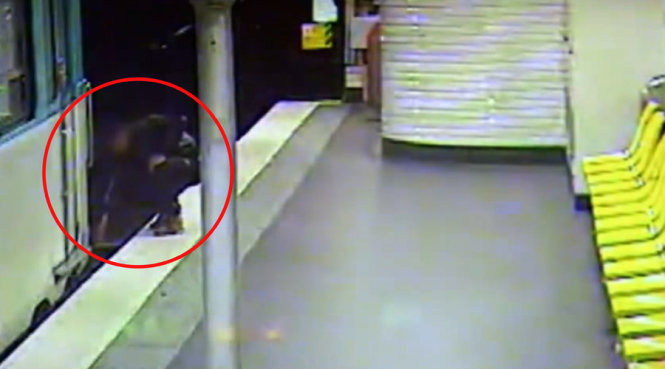 Tên móc túi đang cố gắng kéo nạn nhân của hắn lên khỏi đường ra tàu điện - Ảnh chụp từ clip