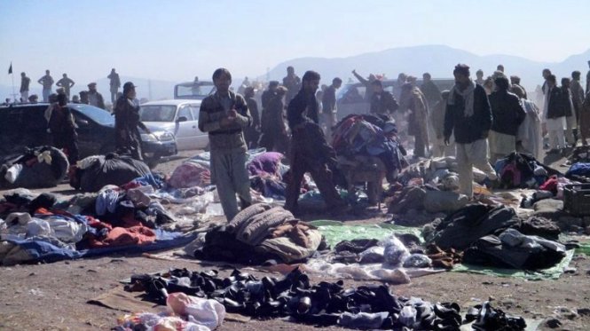 Mọi người đang xác minh vật dụng cá nhân của các nạn nhân tại hiện trường nổ bom ở khu chợ của Pakistan gần biên giới với Afghanistan - Ảnh: EPA