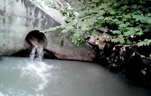 Cô gái chui trong cống nước thải thò chân ra ngoài - Ảnh: Người dân cung cấp
