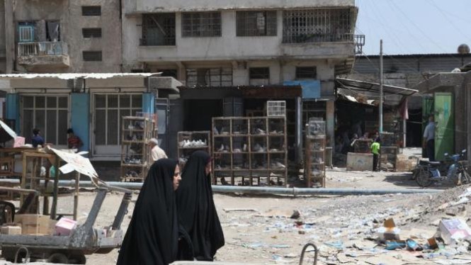 Những người phụ nữ Iraq đi qua khu chợ tại Baghdad sau một vụ nổ bom - Ảnh: AFP