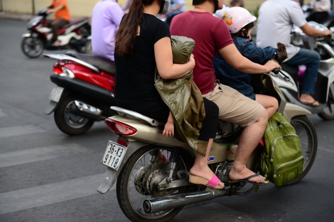 Một đứa trẻ được phụ huynh che áo khoác để chống lạnh trên đường Lê Duẩn, Q. 1 - Ảnh: Thanh Tùng