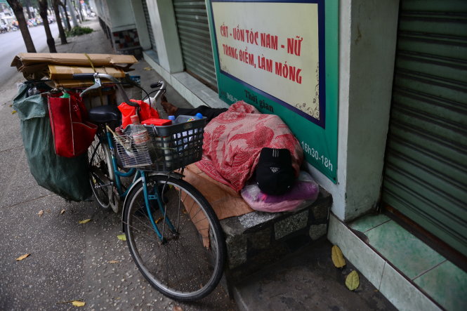 Một người nhặt ve chai co ro ngủ bên lề đường Võ Thị Sáu, Q.3 sau một đêm lao động - Ảnh: Thanh Tùng