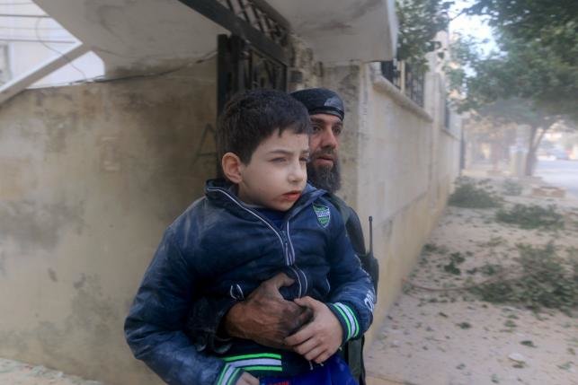 Một nhân viên cứu hộ đang ôm một bé trai bị thương sau các đợt không kích mà các nhà hoạt động tin rằng do không quân Nga tiến hành tại thành phố Idlib, Syria ngày 20-12 - Ảnh: Reuters