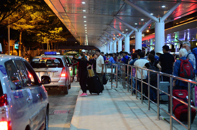 Hành khách đón taxi tại điểm đón mới ở sân bay Tân Sơn Nhất, TP.HCM tối 24-12 - Ảnh: Thanh Tùng