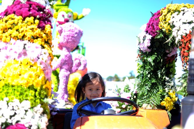 Một em nhỏ đang ngồi trên chiếc xe chở đầy hoa - Ảnh: Lâm Thiên