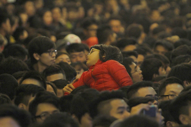 Một bé gái vất vưởng trên vai người bố trong đám đông - Ảnh: Nam Trần
