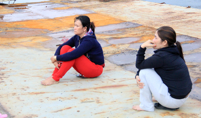 Chị Võ Thị Cảnh (vợ của ngư dân Huỳnh Văn Thạnh trên tàu QNg 98495) cùng vợ của một ngư dân khác ngồi đợi tàu cập cảng - Ảnh: TRƯỜNG TRUNG.