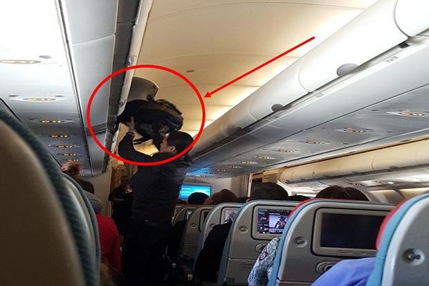 Ảnh cắt từ clip cho thấy hành khách Trung Quốc Qiquan Ma đang lấy trộm tiền trong hành lý của người khác ở khoang chứa đồ trong máy bay - Ảnh: Bangkok Post
