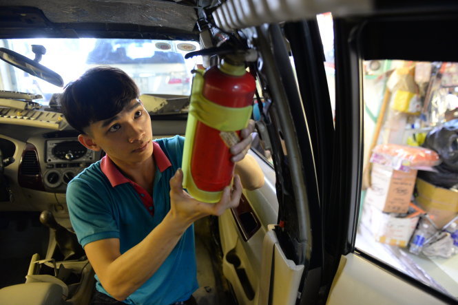 Nhân viên cửa hàng bán bình chữa cháy tại TP.HCM lắp đặt bình chữa cháy trên ôtô của khách hàng Ảnh: Hữu Khoa