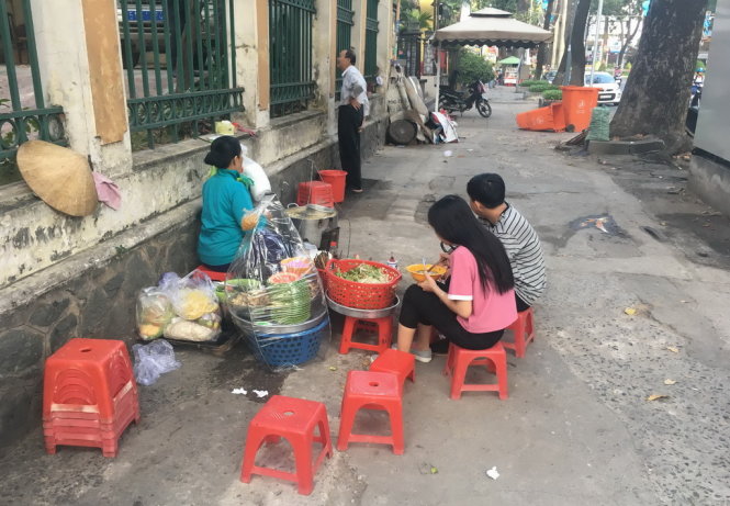 Hai bạn trẻ ngồi ăn sáng trên vỉa hè đường Phạm Ngọc Thạch, Q.1, TP.HCM rất sơ sài - Ảnh: Quang Định