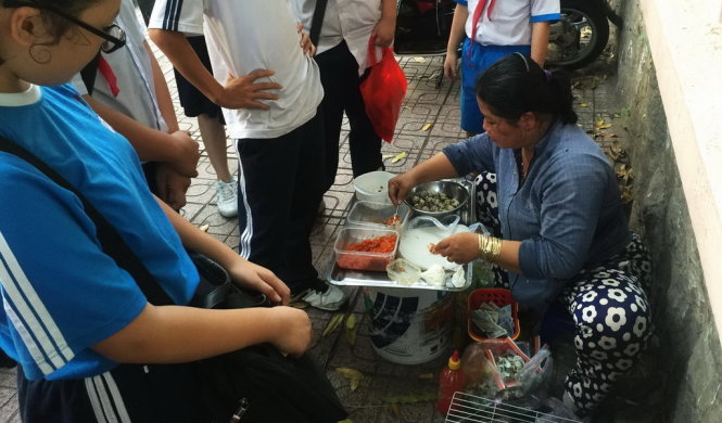 Học sinh ăn uống, quà vặt trước cổng trường THCS Lê Quý Đôn, Q.3, không đảm bảo VSATTP - Ảnh: Tự Trung
