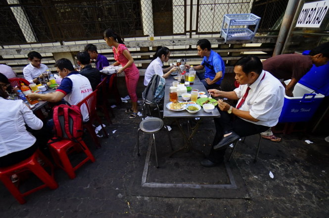 Nhiều người ngồi ăn cơm trên vỉa hè đường Nguyễn Thị Minh Khai, Q.3, TP.HCM chiều 9-1, phía dưới đầy rác - Ảnh: Quang Định
