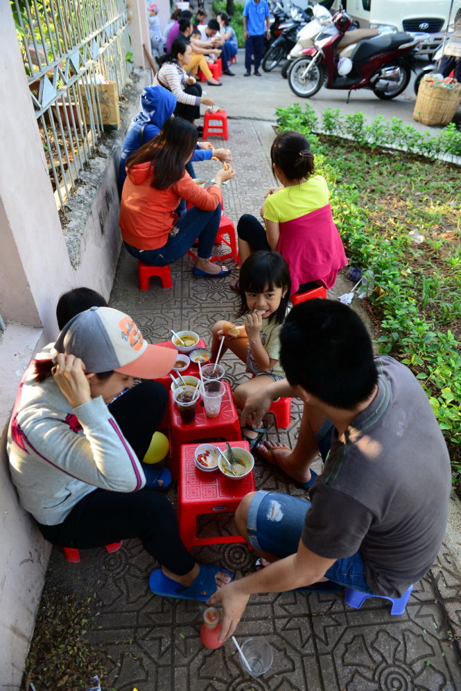 Trẻ em cùng gia đình ngồi ăn phá lấu trên vỉa hè đường Bà Huyện Thanh Quan, Q.3, TP.HCM chiều 9-1 - Ảnh: Quang Định