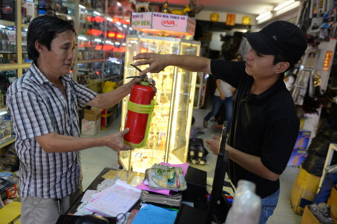Một tài xế ôtô mua bình chữa cháy để trang bị trên xe tại một cửa hàng bán phụ tùng ôtô trên đường An Dương Vương, Q.5, TP.HCM - Ảnh: Hữu Khoa
