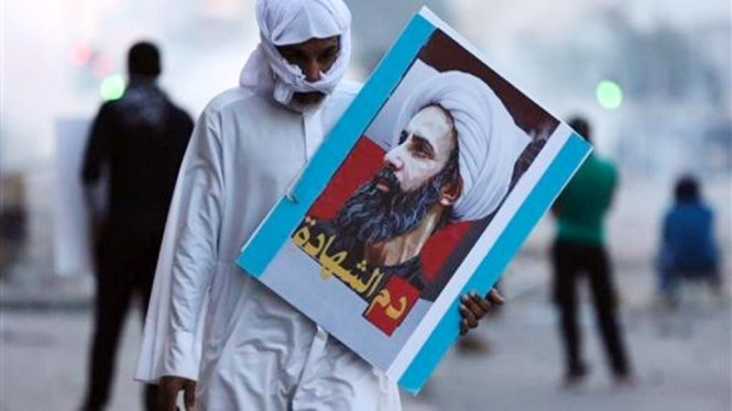 Một người Bamang ảnh chân dung của Sheikh Nimr al-Nimr trong các cuộc đụng độ với cảnh sát ở Sitra, Bahrain hồi cuối tuần qua - Ảnh: AP