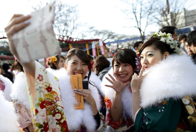 Các thiếu nữ chụp ảnh kỷ niệm trong lễ hội trưởng thành diễn ra ở công viên giải trí tại Tokyo ngày 11-1 - Ảnh: Reuters