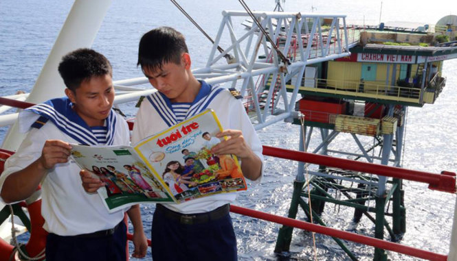 Trung sĩ Dương Minh Thắng (phải) và hạ sĩ Nguyễn Trung Quân ở nhà dàn DK1/15 tại bãi Phúc Nguyên - thềm lục địa phía Nam đang đọc đặc san xuân Bính Thân của Tuổi Trẻ - Ảnh: Thái Lộc