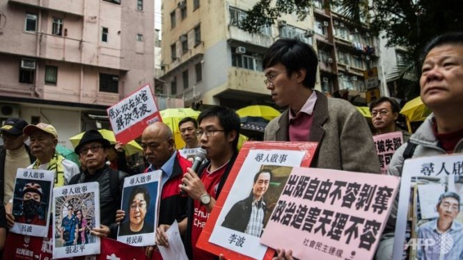 Người Hong Kong cầm ảnh chân dung của hai ông chủ nhà xuất bản Mighty Current và các nhân viên mất tích bí ẩn nhiều ngày qua - Ảnh: AFP