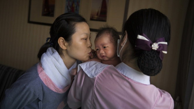 Một em bé Trung Quốc đang trong vòng tay yêu thương của gia đình - Ảnh: Reuters