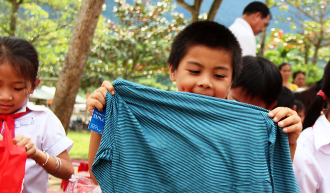Một em học sinh vui sướng, thích thú khi thử chiếc áo ngay sau khi được tặng - Ảnh: PHAN THÀNH
