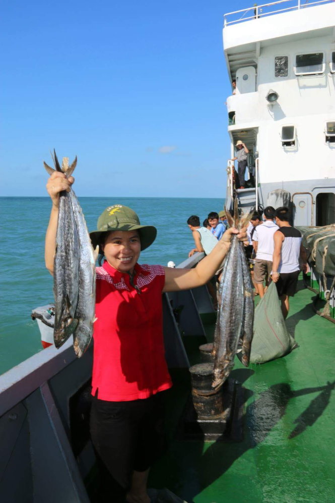 Phóng viên Bich Trang của báo Quân đội nhân dân và những con cá thu ướp muối vừa được ngư dân tặng. Ảnh: Thái Lộc